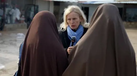 The BBC's Orla Guerin speaks to two women who have their back turned towards the camera.
