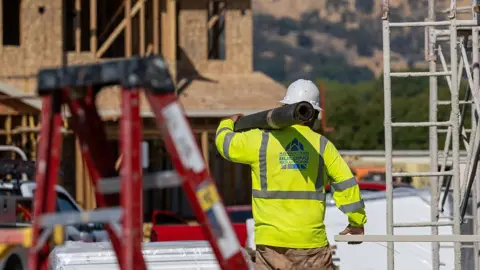 Bloomberg via Getty Images A worker carries materials outside of a new home under construction at the Lilac Ridge community by Lennar Homes in Vacaville, California, US, on Wednesday, Oct. 8, 2025.