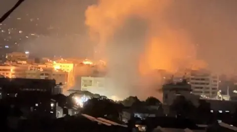 The night sky light up in orange as smoke is seen rising from buildings in Lebanon