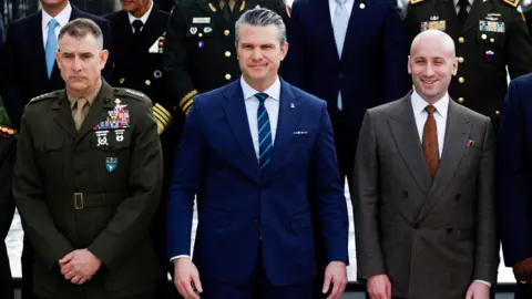 Reuters US Secretary of Defence Pete Hegseth standing in a blue suit and tie.