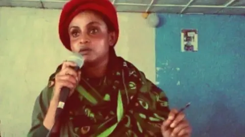 Rahwa Gebremedhin Rahwa Gebremedhin wearing a military uniform and a red beret holding a microphone