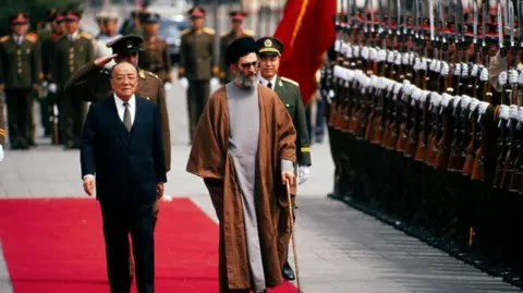 Getty Images Chinese President Yang Shangkun (1907 - 1998) (center left) and Iranian President Ali Khamenei (center right) walk together during a welcoming ceremony for the latter's State Visit, Beijing, China, May 11, 1989.