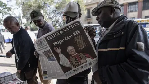 AFP via Getty Images A group of men at a news stand with one of them holding up the Daily Nation. The headline is about Pope Leo XIV.