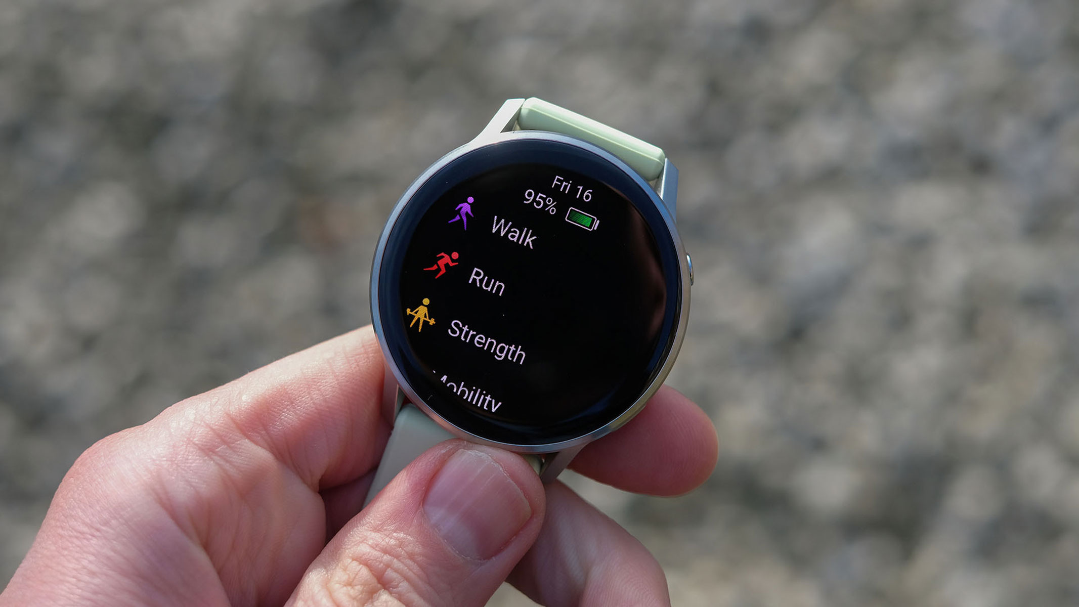 a close-up picture of our reviewer holding the Garmin Venu 4 smartwatch displaying the workout modes